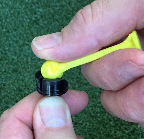 A person holding a yellow ear plug in their hand.