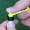 A person holding a yellow ear plug in their hand.