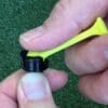 A person holding a yellow plastic golf tee and bottle.