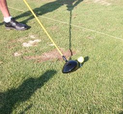 A person holding onto the string to swing at a golf ball.